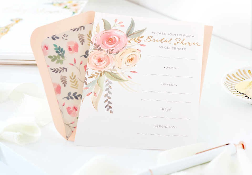 A floral wedding shower invitation on a table with an envelope