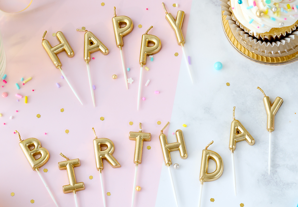 Gold candles on a table spelling out Happy Birthday